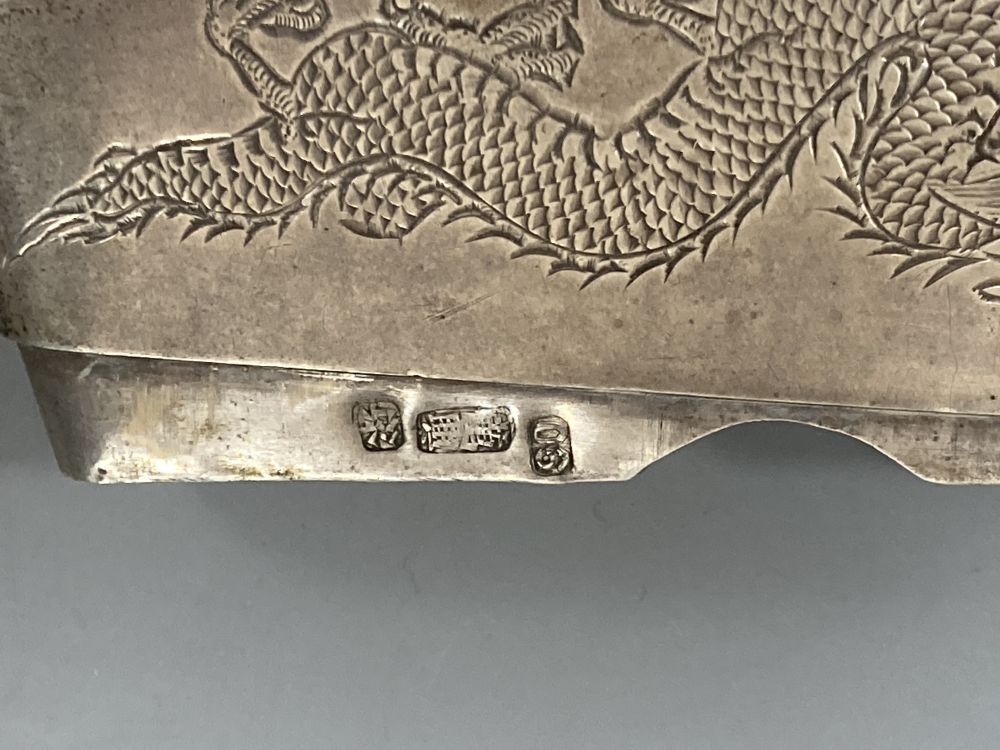 A Chinese white metal concave card case engraved with a dragon, 84mm and a Chinese metal circular box and cover.